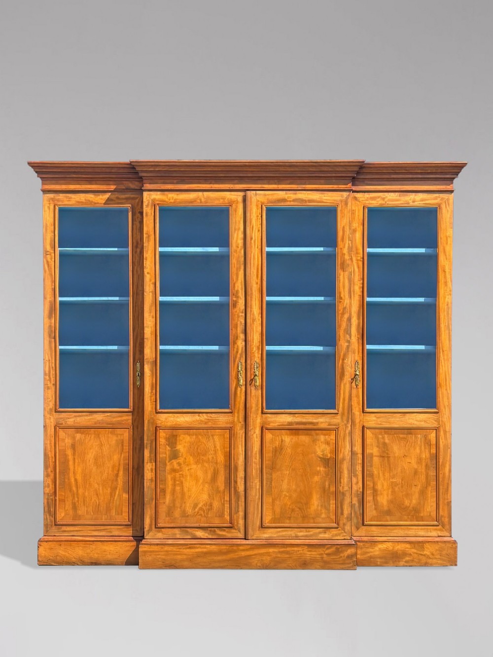 A 19th-century French Louis Philippe walnut four-door bookcase featuring glazed upper doors, panelled lower sections, and a blue painted interior.