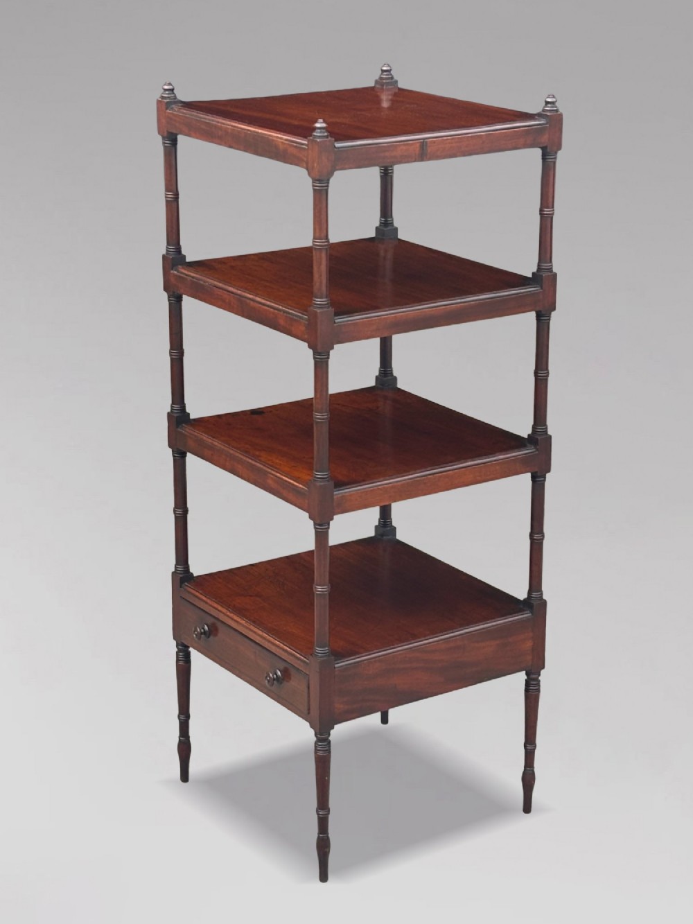 A four-tier George III mahogany whatnot features turned corner columns topped with small finials and includes a single drawer built into the lowest shelf.