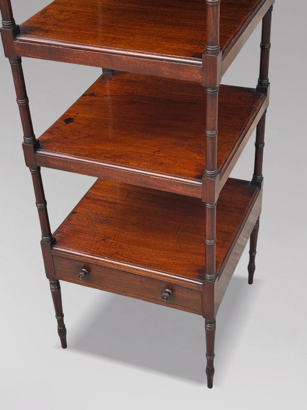 A four-tier George III mahogany whatnot features turned corner columns topped with small finials and includes a single drawer built into the lowest shelf. View IV