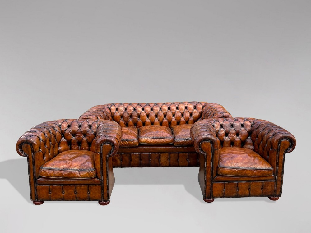 A Victorian three-seater Chesterfield sofa with brown deep-buttoned leather, three seat cushions, brass stud trim, and turned feet. View X