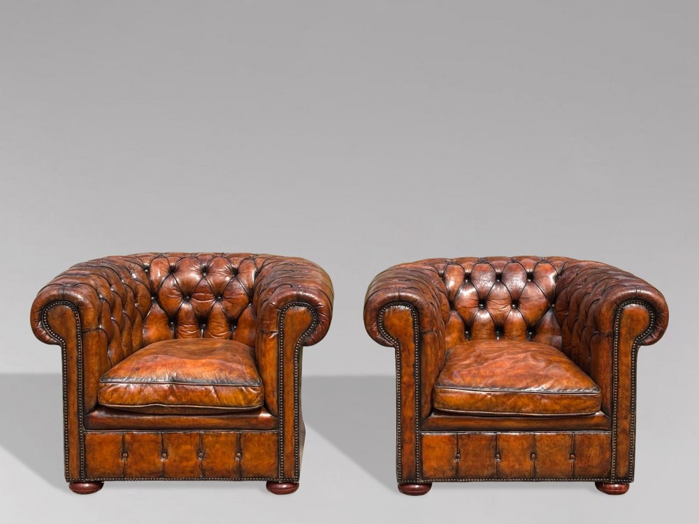 A pair of late Victorian deep-buttoned brown leather Chesterfield club armchairs with rolled arms, brass studding, and turned wooden feet. View III