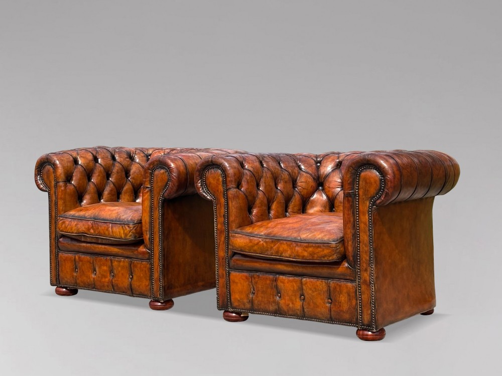 A pair of late Victorian deep-buttoned brown leather Chesterfield club armchairs with rolled arms, brass studding, and turned wooden feet. View VII
