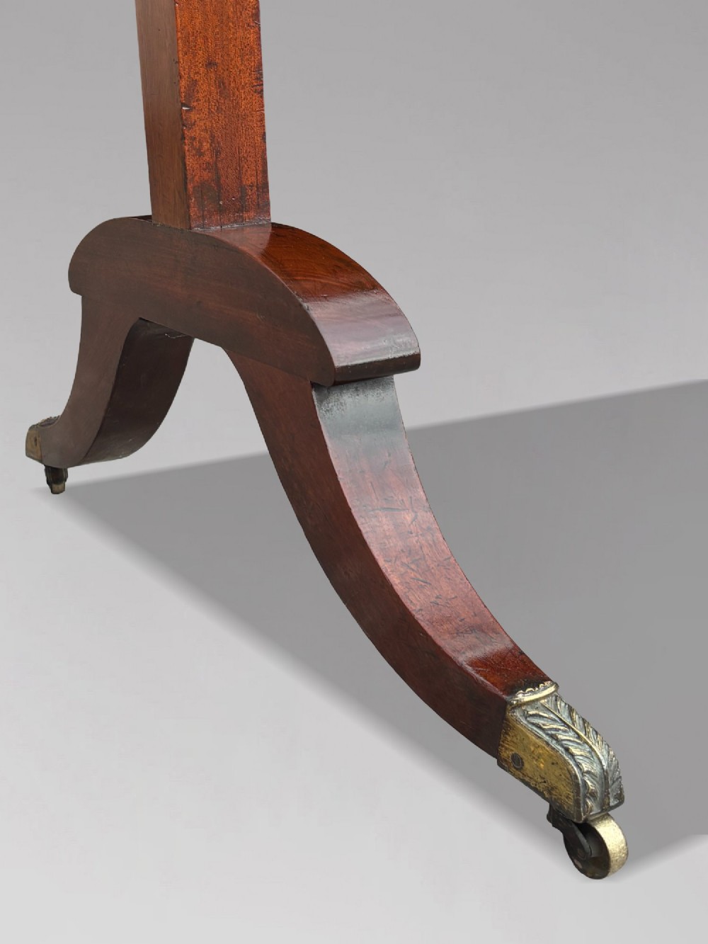 An early 19th-century Regency mahogany cheval mirror featuring turned uprights, brass candle sconces, finials, and splayed legs on brass castors. View IX