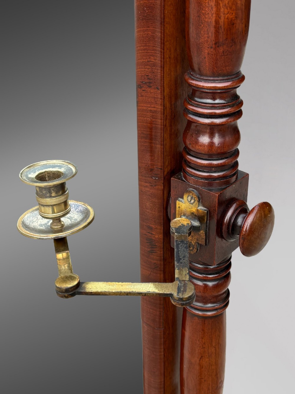 An early 19th-century Regency mahogany cheval mirror featuring turned uprights, brass candle sconces, finials, and splayed legs on brass castors. View XIII