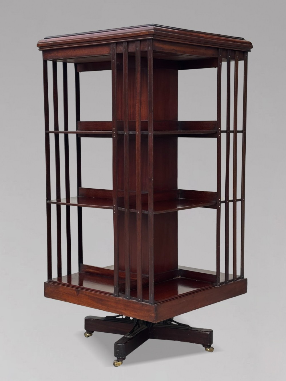 A four-tier Victorian mahogany revolving bookcase featuring vertical slatted sides, a square top, and a rotating base on brass castors. View II