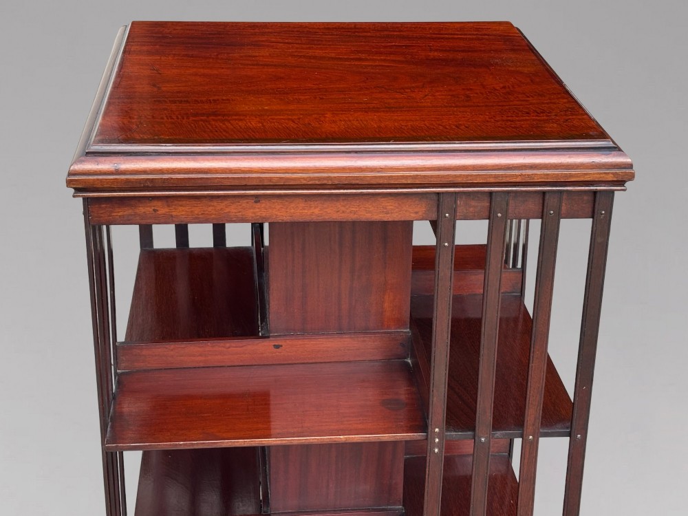 A four-tier Victorian mahogany revolving bookcase featuring vertical slatted sides, a square top, and a rotating base on brass castors. View III