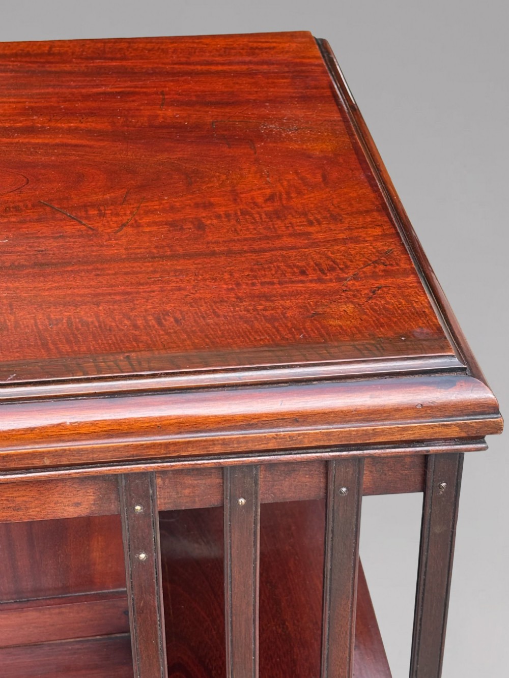 A four-tier Victorian mahogany revolving bookcase featuring vertical slatted sides, a square top, and a rotating base on brass castors. View VII