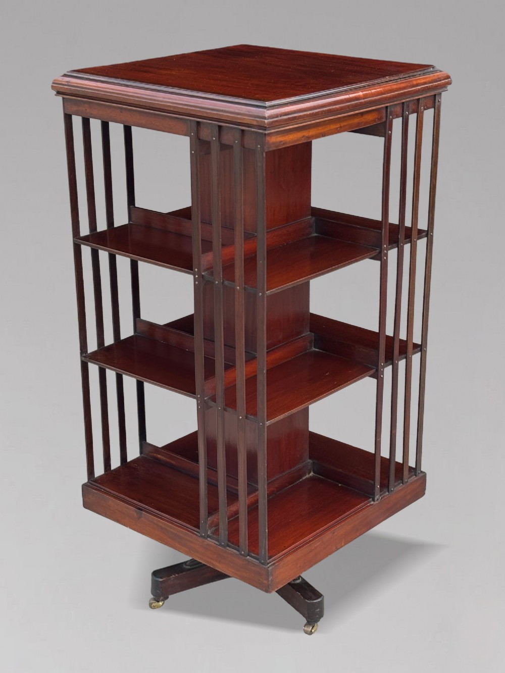 A four-tier Victorian mahogany revolving bookcase featuring vertical slatted sides, a square top, and a rotating base on brass castors. View IX