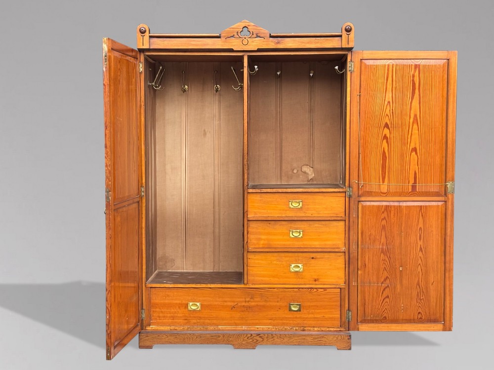 A late 19th-century pitch pine Arts and Crafts wardrobe featuring vertical slatted upper door panels, chevron lower panels, and a carved cresting rail. View VI