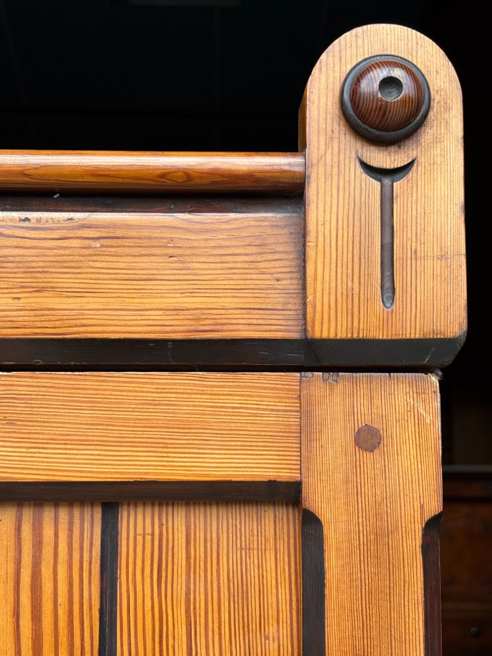 A late 19th-century pitch pine Arts and Crafts wardrobe featuring vertical slatted upper door panels, chevron lower panels, and a carved cresting rail. View VIII