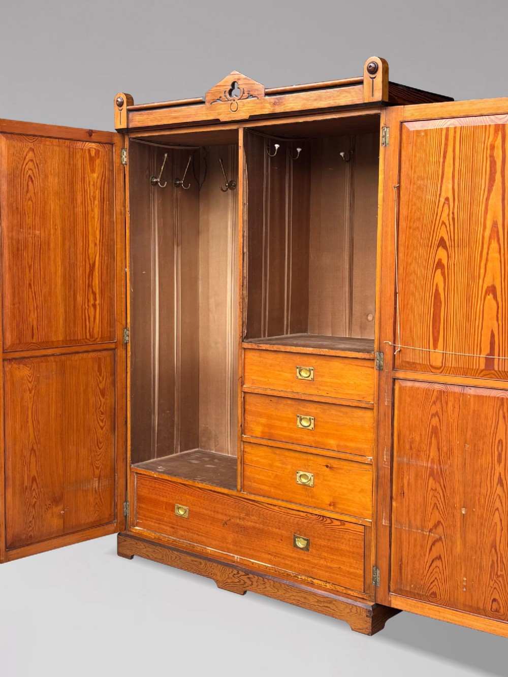 A late 19th-century pitch pine Arts and Crafts wardrobe featuring vertical slatted upper door panels, chevron lower panels, and a carved cresting rail. View X
