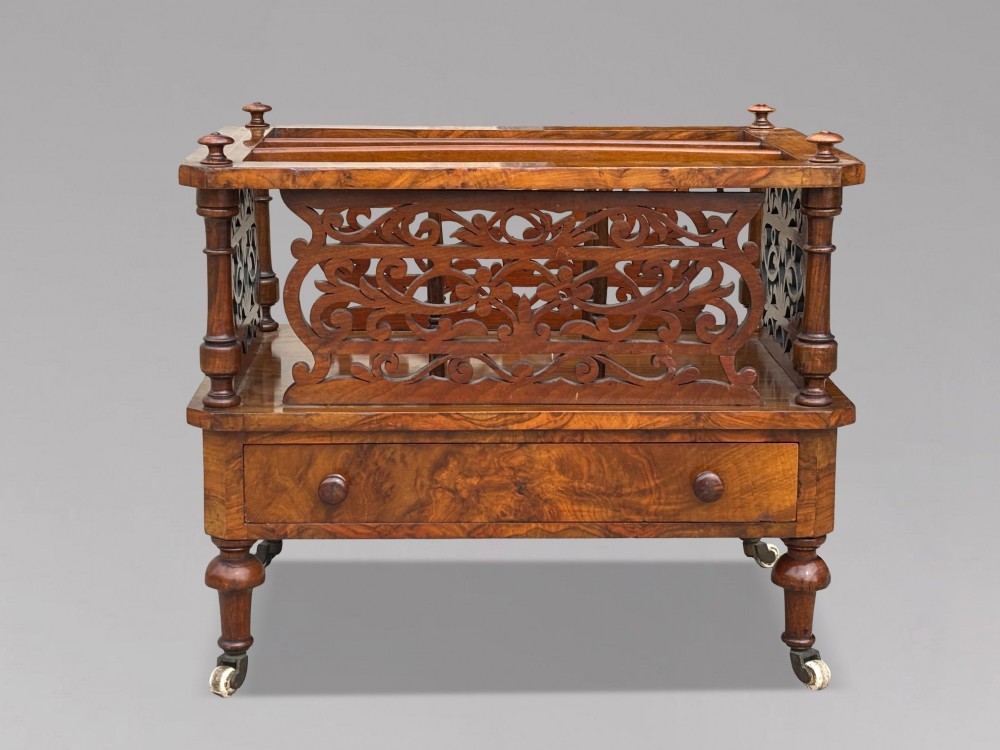 A mid-19th-century Victorian walnut music canterbury featuring open fretwork dividers, turned corner columns, a single base drawer, and turned legs with ceramic castors. View IV