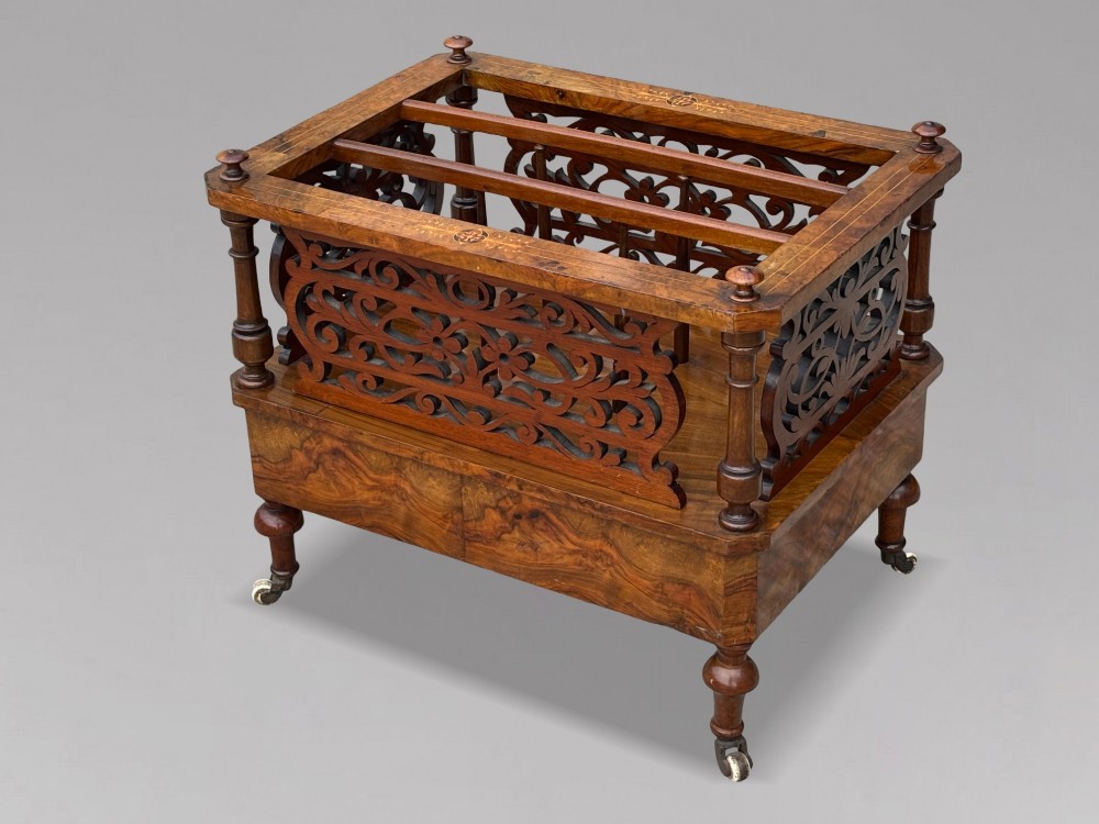 A mid-19th-century Victorian walnut music canterbury featuring open fretwork dividers, turned corner columns, a single base drawer, and turned legs with ceramic castors. View VI