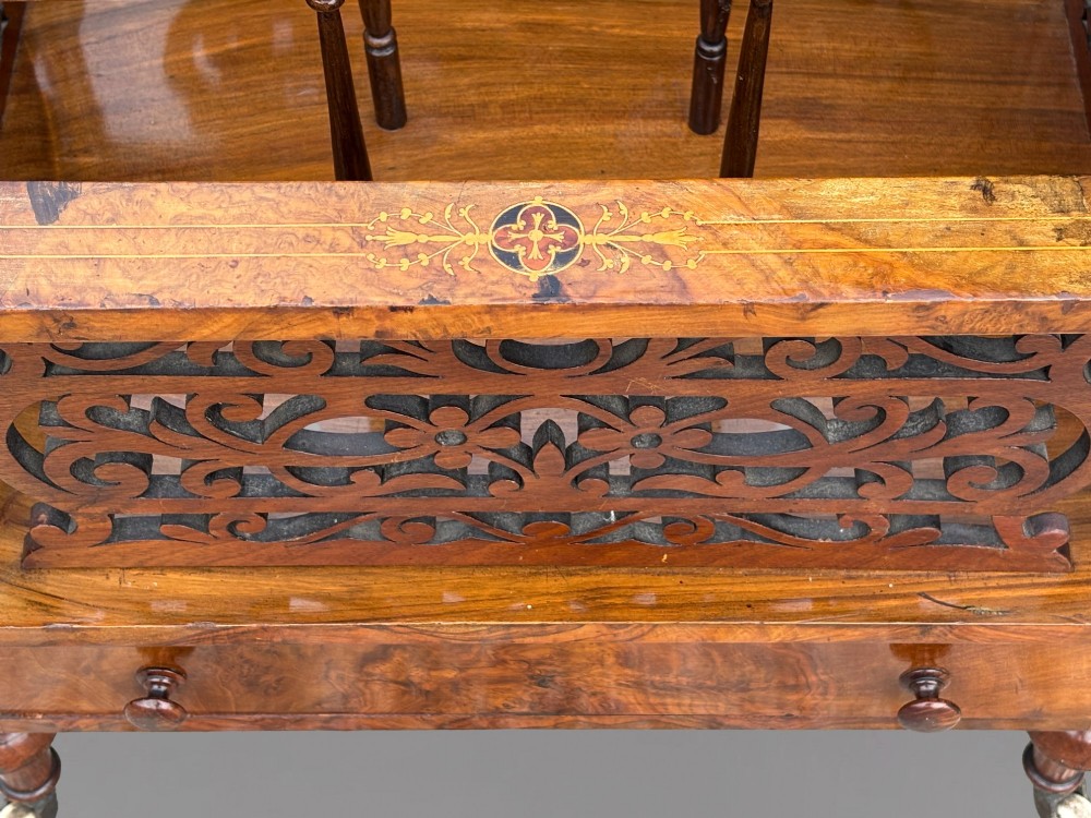 A mid-19th-century Victorian walnut music canterbury featuring open fretwork dividers, turned corner columns, a single base drawer, and turned legs with ceramic castors. View IX