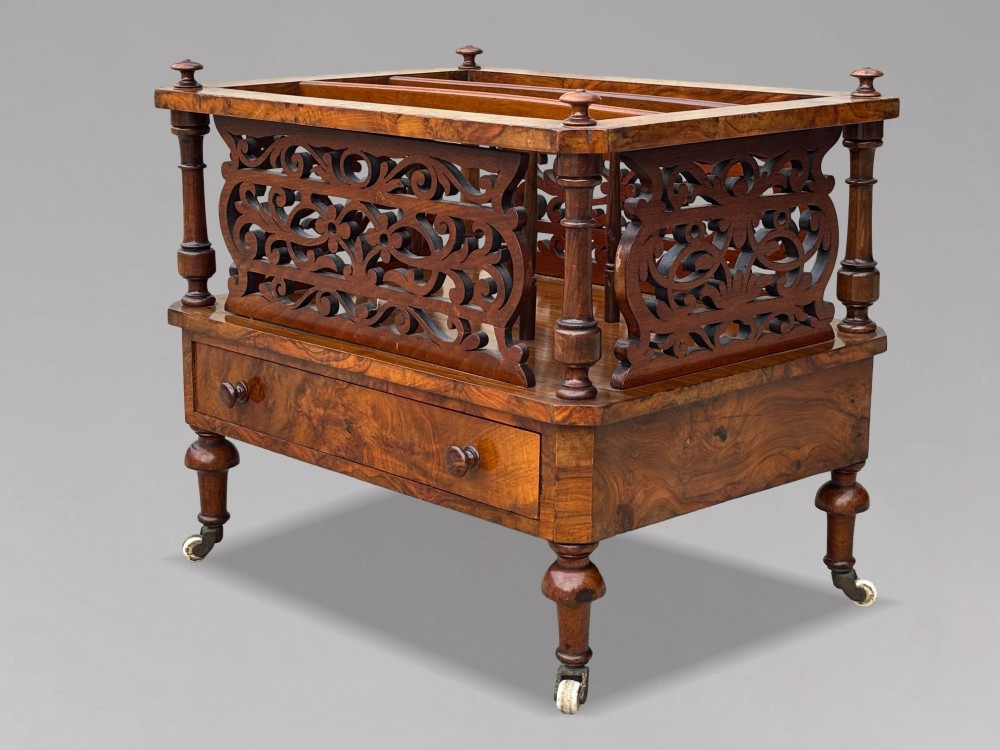 A mid-19th-century Victorian walnut music canterbury featuring open fretwork dividers, turned corner columns, a single base drawer, and turned legs with ceramic castors. View XI