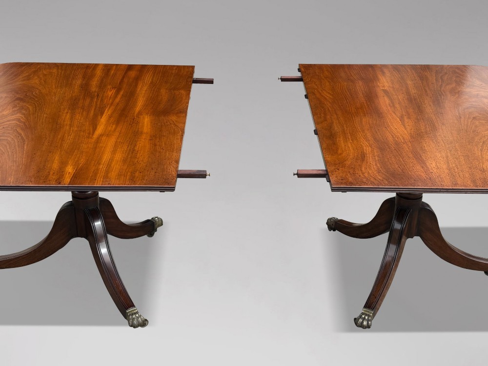 An early 19th-century Georgian mahogany twin pedestal dining table with a removable extension leaf, turned support pillars, and splayed legs ending in brass toe castors. View III