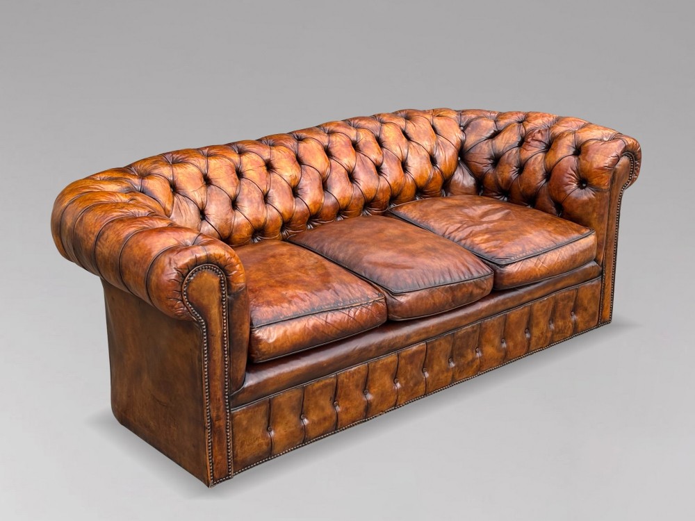 A nineteenth-century Victorian three-seater Chesterfield sofa upholstered in aged warm brown leather with deep button tufting and nailhead trim. View II