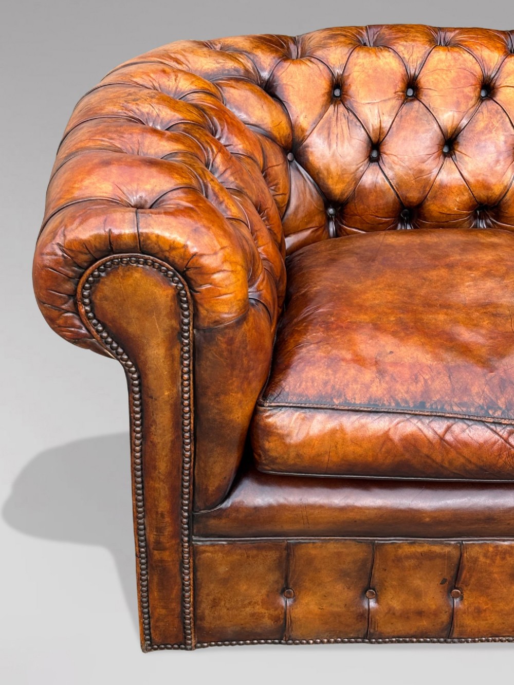 A nineteenth-century Victorian three-seater Chesterfield sofa upholstered in aged warm brown leather with deep button tufting and nailhead trim. View IV