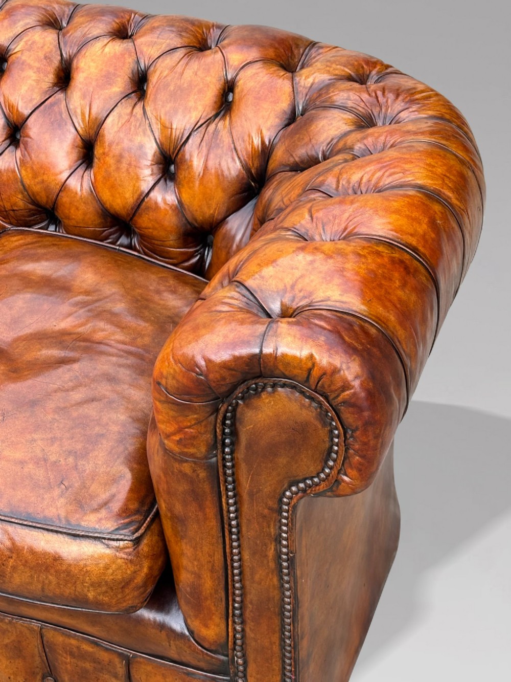 A nineteenth-century Victorian three-seater Chesterfield sofa upholstered in aged warm brown leather with deep button tufting and nailhead trim. View VI