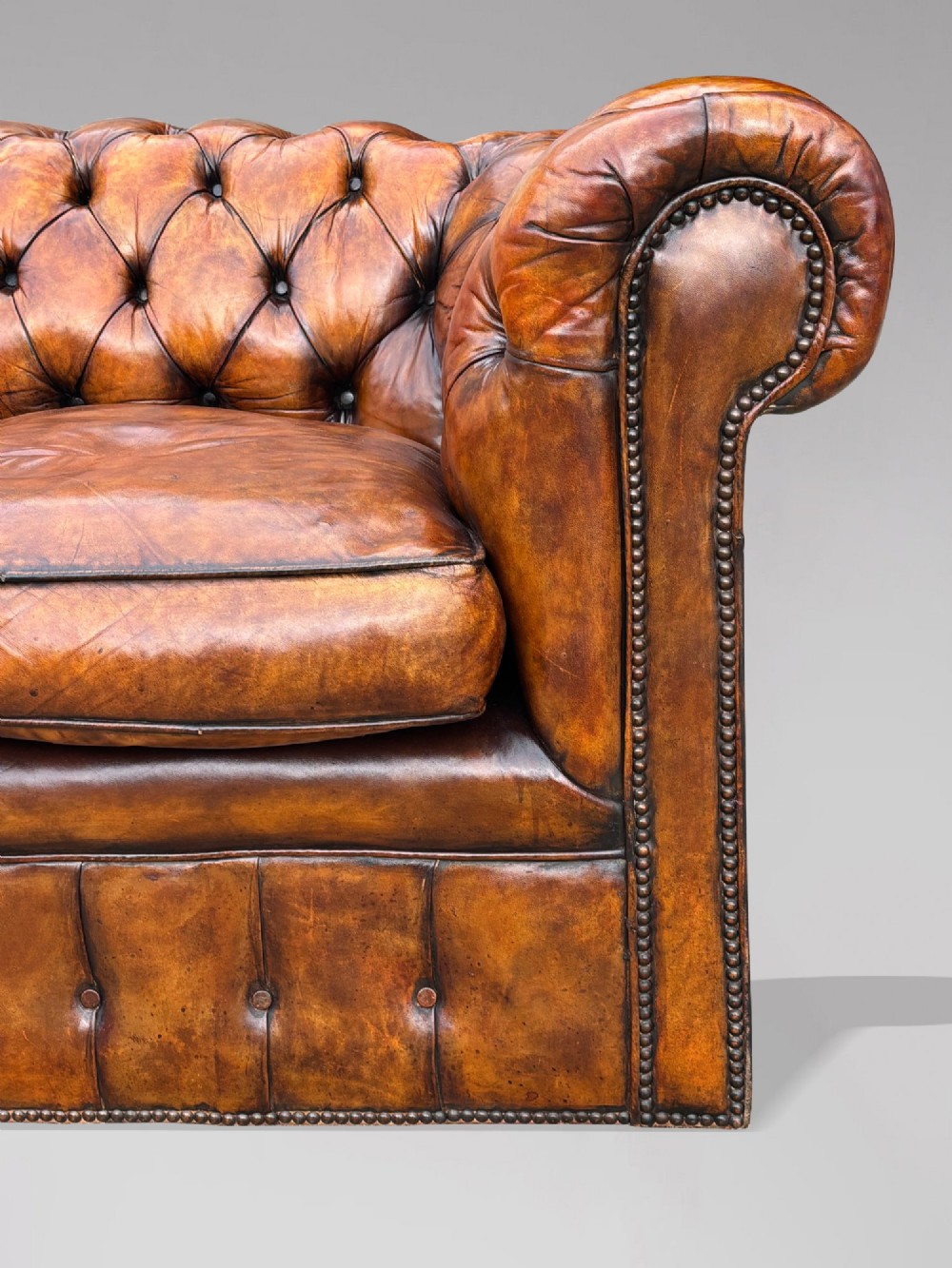 A nineteenth-century Victorian three-seater Chesterfield sofa upholstered in aged warm brown leather with deep button tufting and nailhead trim. View VII