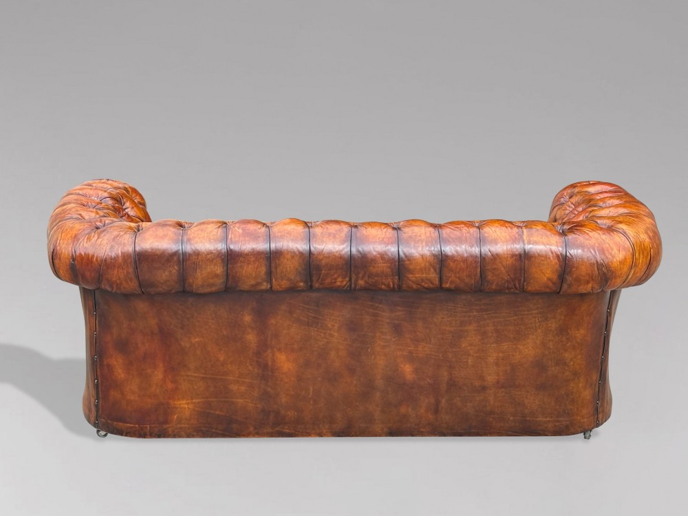 A nineteenth-century Victorian three-seater Chesterfield sofa upholstered in aged warm brown leather with deep button tufting and nailhead trim. View VIII