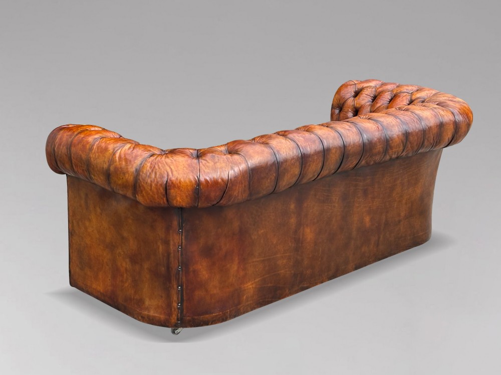 A nineteenth-century Victorian three-seater Chesterfield sofa upholstered in aged warm brown leather with deep button tufting and nailhead trim. View IX