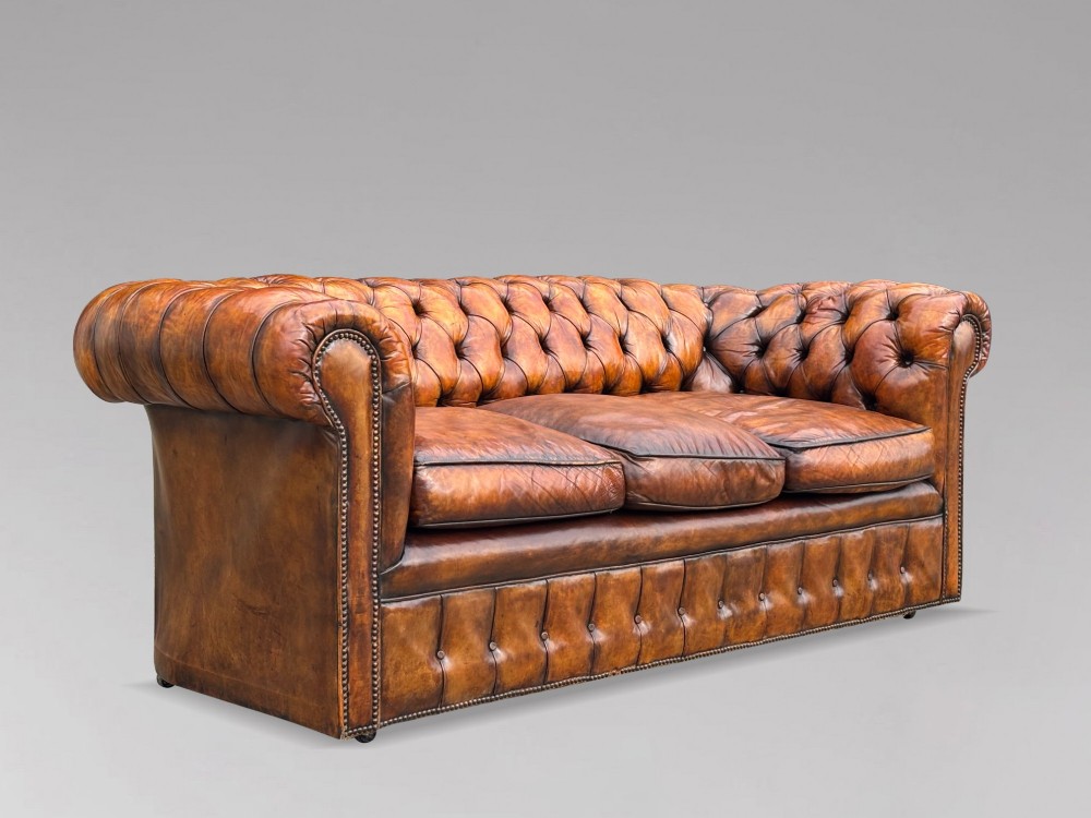 A nineteenth-century Victorian three-seater Chesterfield sofa upholstered in aged warm brown leather with deep button tufting and nailhead trim. View X