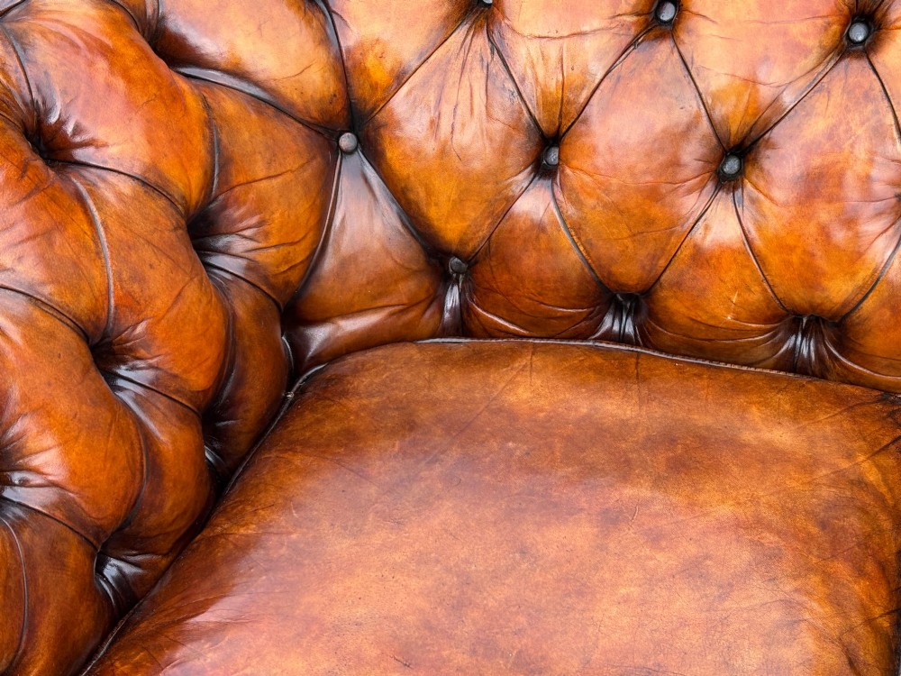 A nineteenth-century Victorian three-seater Chesterfield sofa upholstered in aged warm brown leather with deep button tufting and nailhead trim. View XI