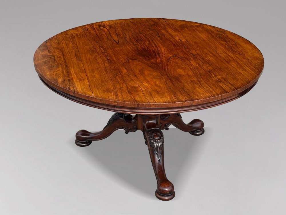A circular William IV period rosewood centre table with a figured top on a carved pedestal and tripod base. View II