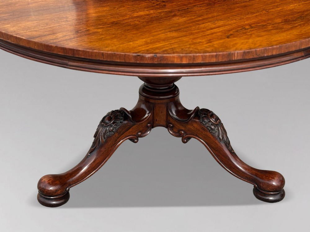 A circular William IV period rosewood centre table with a figured top on a carved pedestal and tripod base. View III