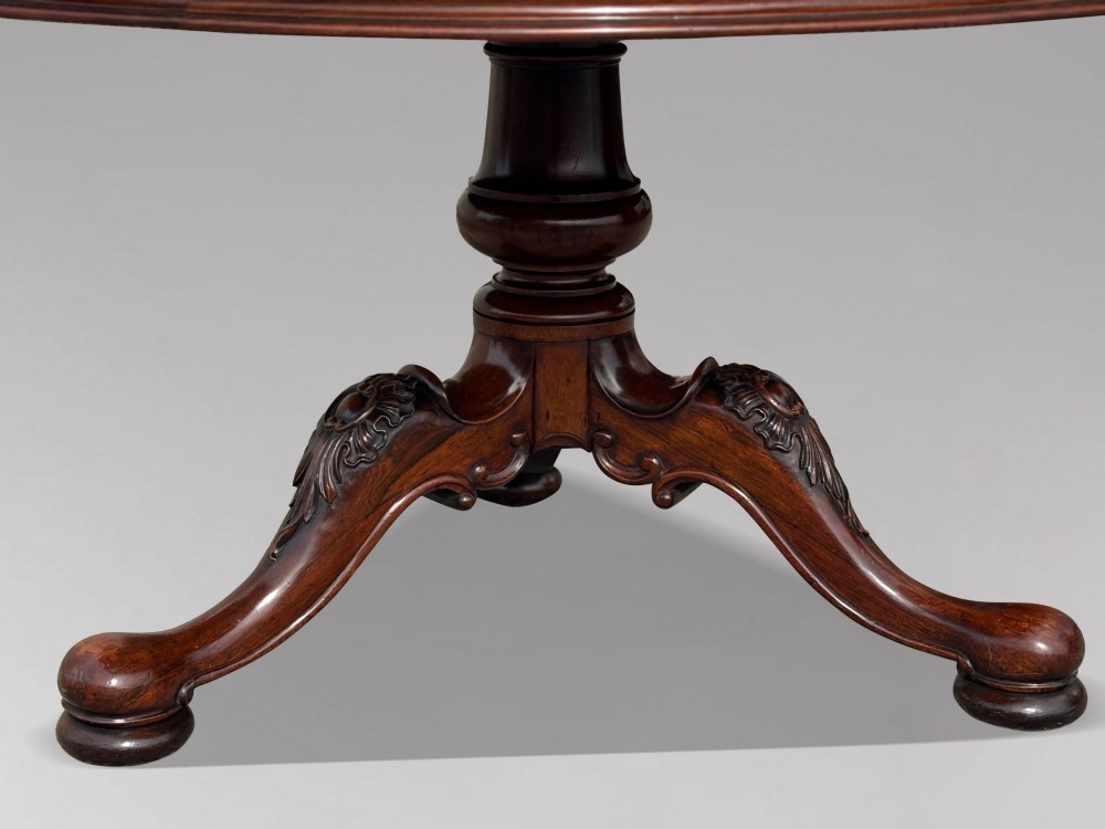 A circular William IV period rosewood centre table with a figured top on a carved pedestal and tripod base. View IV