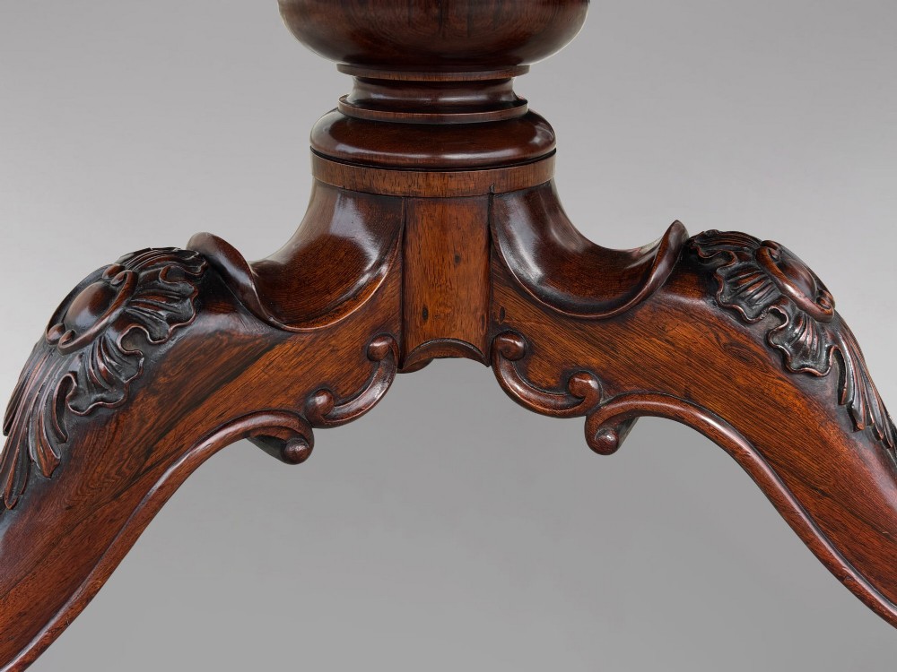 A circular William IV period rosewood centre table with a figured top on a carved pedestal and tripod base. View X