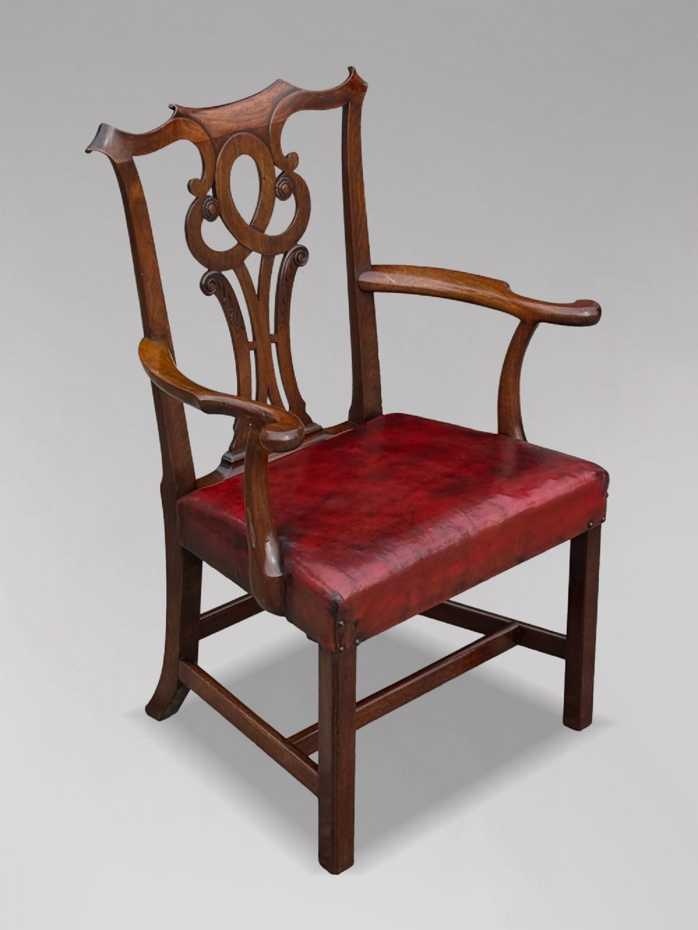 An 18th-century George III mahogany Chippendale armchair featuring a carved pierced splat back, curved arms, and a red leather upholstered seat.