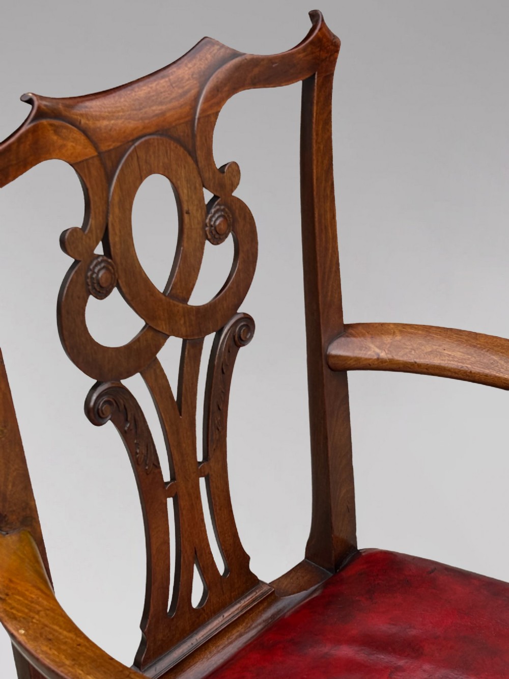 An 18th-century George III mahogany Chippendale armchair featuring a carved pierced splat back, curved arms, and a red leather upholstered seat. View IV