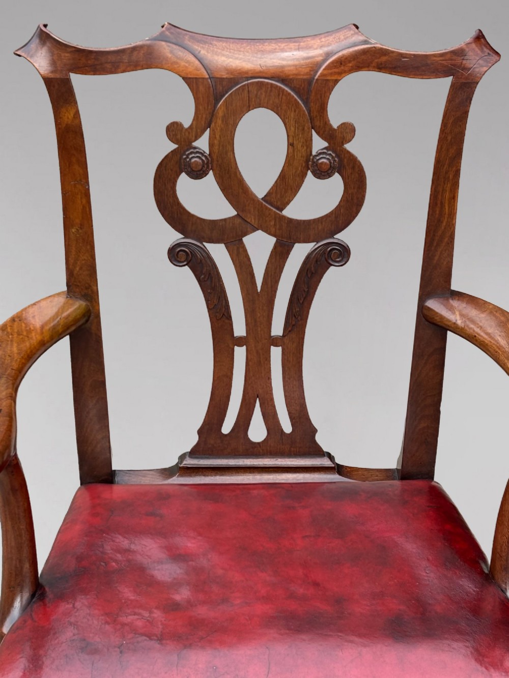 An 18th-century George III mahogany Chippendale armchair featuring a carved pierced splat back, curved arms, and a red leather upholstered seat. View V