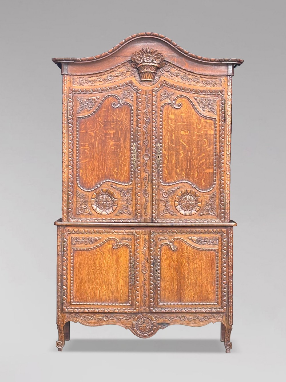 An 18th-century French Louis XVI carved oak buffet deux corps featuring two upper panelled doors topped with a floral basket carving above a two-door base resting on short scrolled feet. View II