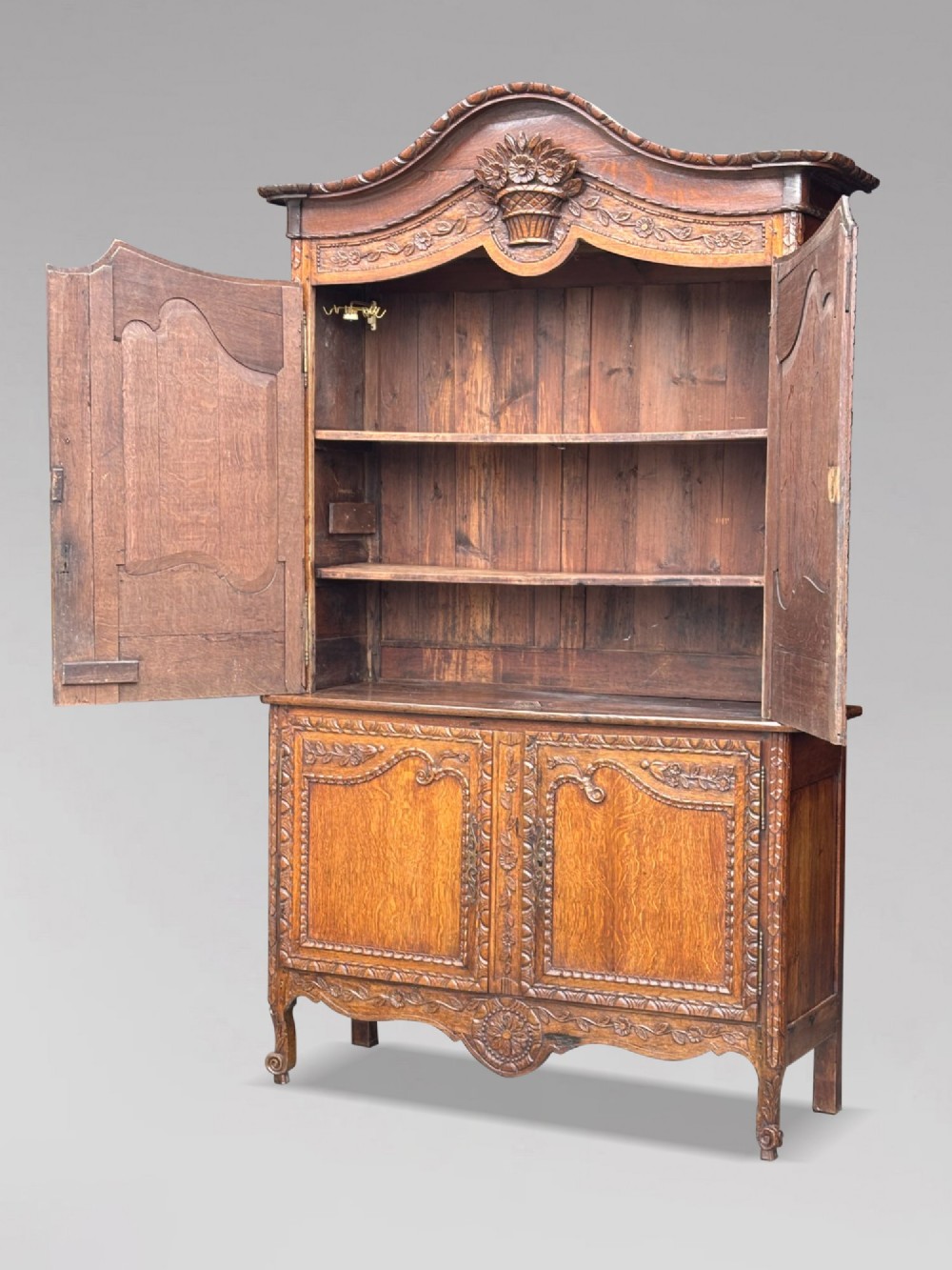 An 18th-century French Louis XVI carved oak buffet deux corps featuring two upper panelled doors topped with a floral basket carving above a two-door base resting on short scrolled feet. View III