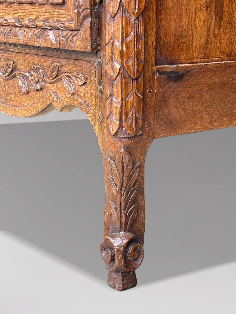 An 18th-century French Louis XVI carved oak buffet deux corps featuring two upper panelled doors topped with a floral basket carving above a two-door base resting on short scrolled feet. View V