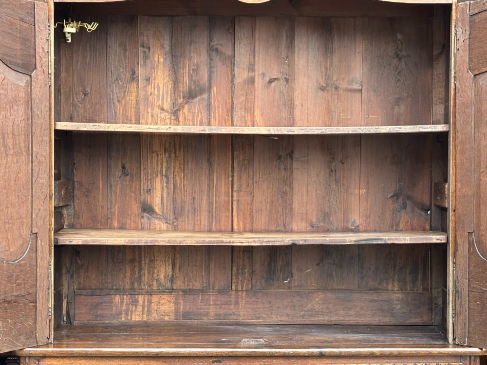 An 18th-century French Louis XVI carved oak buffet deux corps featuring two upper panelled doors topped with a floral basket carving above a two-door base resting on short scrolled feet. View IX