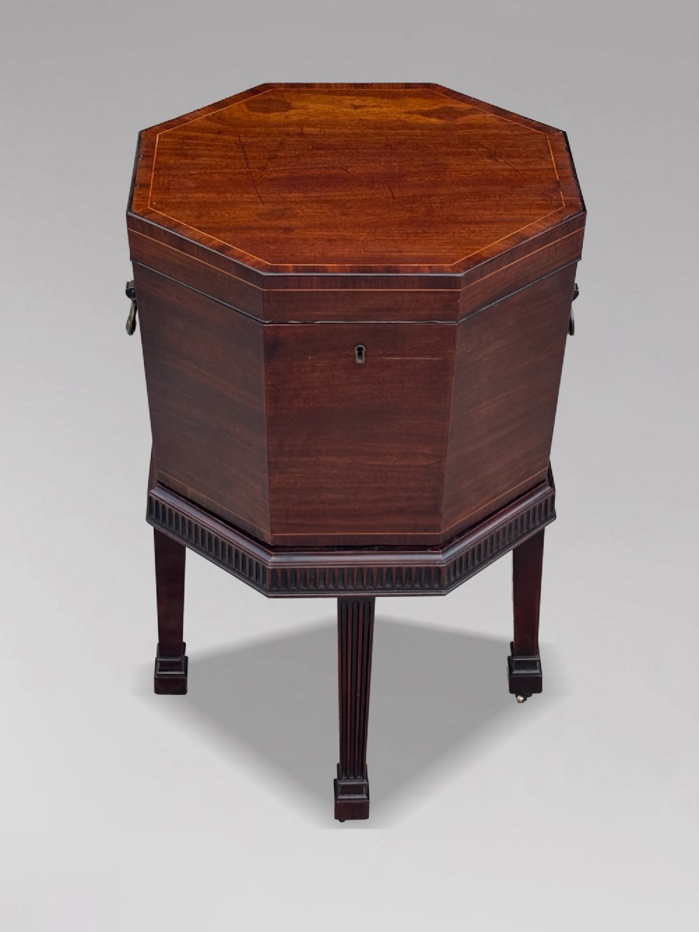 An eighteenth-century octagonal mahogany wine cooler featuring brass side handles, a keyhole detail, boxwood inlay, and fluted legs on castors. View XI