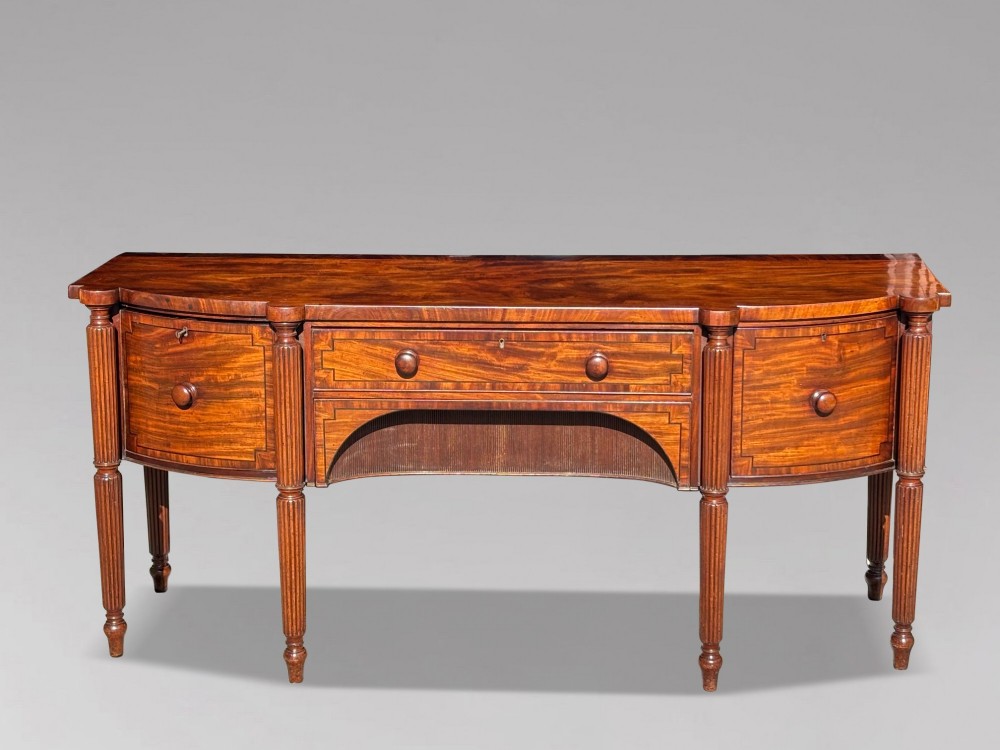 An antique 19th-century William IV mahogany sideboard featuring reeded fluted legs, line inlay, and a central drawer above an arched recess. View II