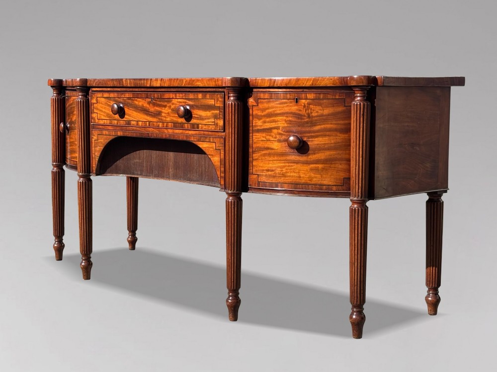 An antique 19th-century William IV mahogany sideboard featuring reeded fluted legs, line inlay, and a central drawer above an arched recess. View VIII