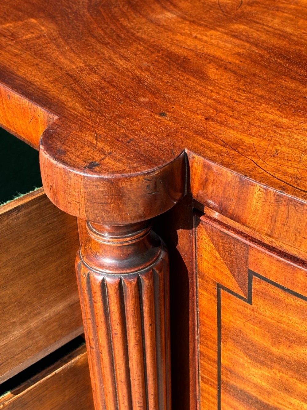 An antique 19th-century William IV mahogany sideboard featuring reeded fluted legs, line inlay, and a central drawer above an arched recess. View IX