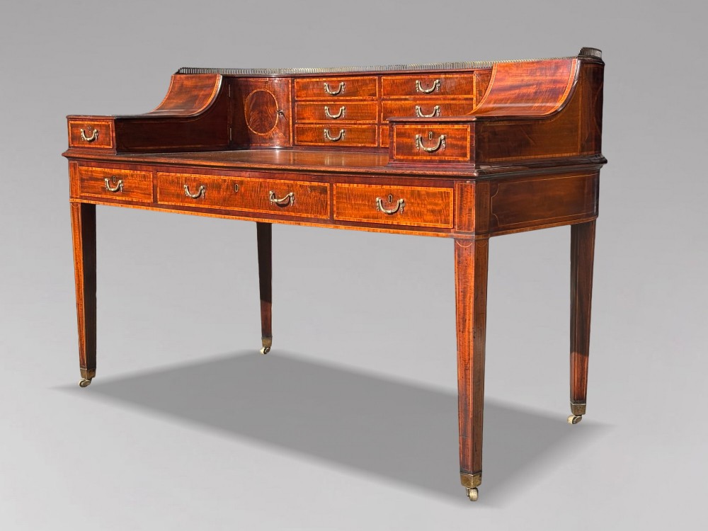 An 18th-century George III mahogany Carlton House desk with inlaid marquetry, a leather writing surface, small upper drawers, and tapered legs on brass castors. View II