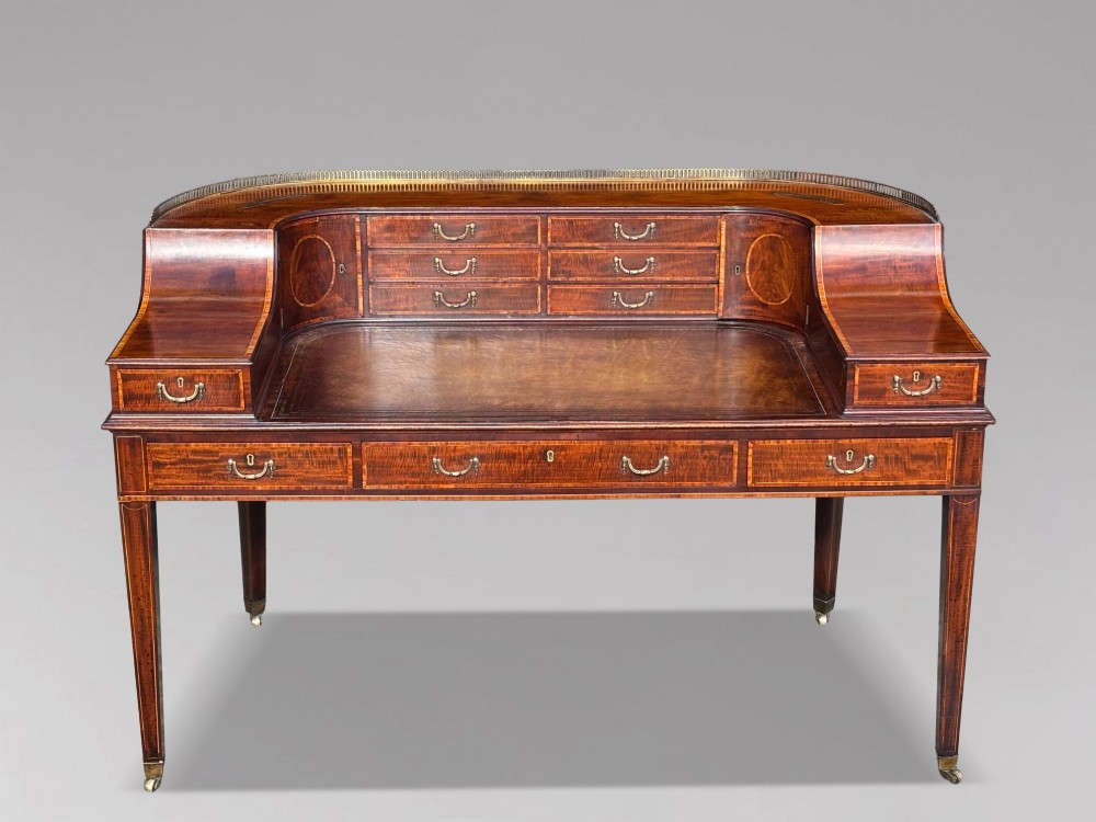 An 18th-century George III mahogany Carlton House desk with inlaid marquetry, a leather writing surface, small upper drawers, and tapered legs on brass castors. View III