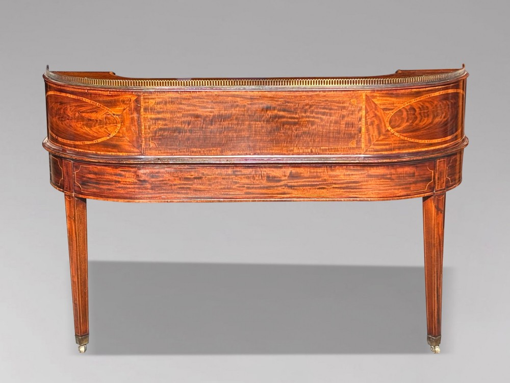 An 18th-century George III mahogany Carlton House desk with inlaid marquetry, a leather writing surface, small upper drawers, and tapered legs on brass castors. View V