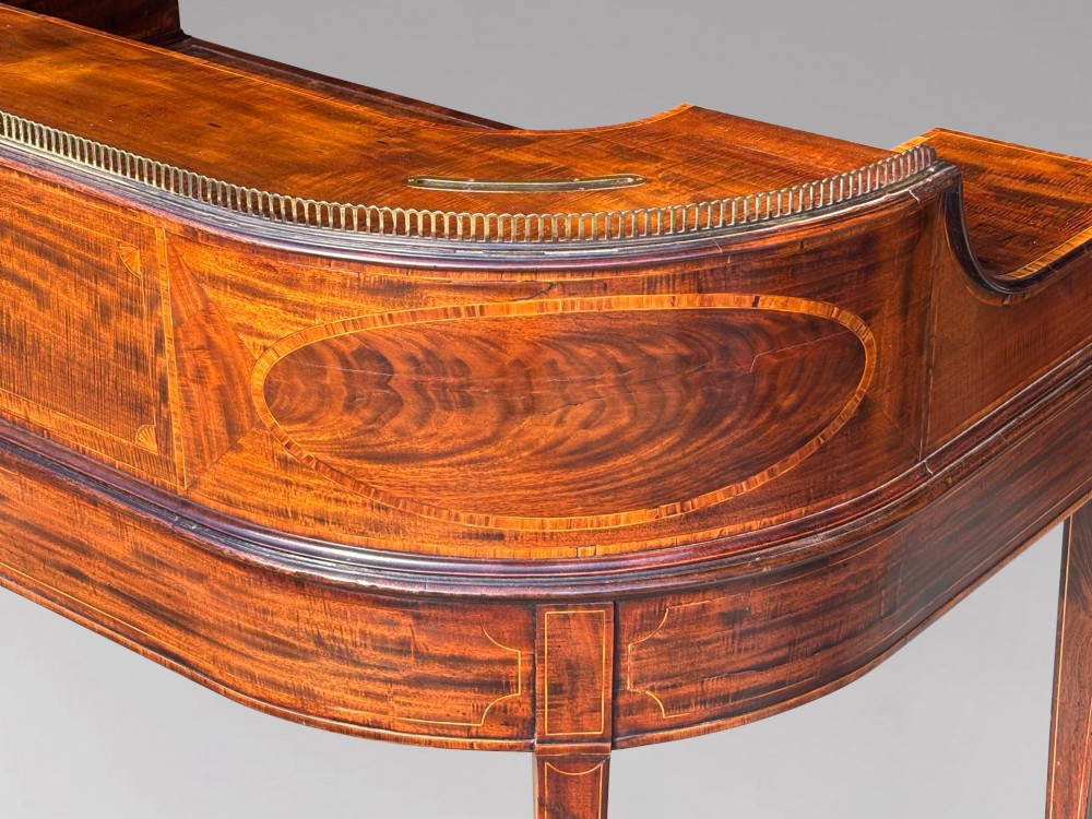 An 18th-century George III mahogany Carlton House desk with inlaid marquetry, a leather writing surface, small upper drawers, and tapered legs on brass castors. View VI