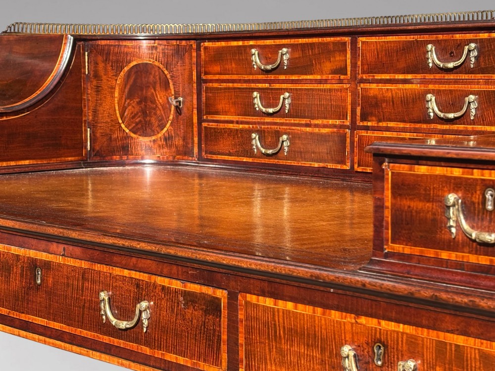 An 18th-century George III mahogany Carlton House desk with inlaid marquetry, a leather writing surface, small upper drawers, and tapered legs on brass castors. View VII