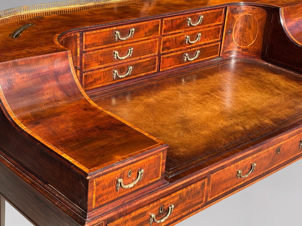 An 18th-century George III mahogany Carlton House desk with inlaid marquetry, a leather writing surface, small upper drawers, and tapered legs on brass castors. View VIII
