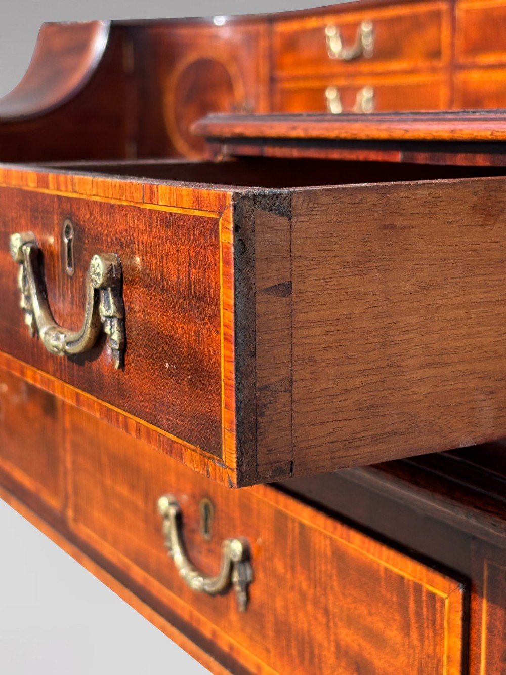 An 18th-century George III mahogany Carlton House desk with inlaid marquetry, a leather writing surface, small upper drawers, and tapered legs on brass castors. View IX